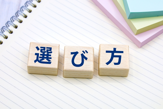 青い色の文字で選び方と書かれた木のブロックとカラフルの付箋とリングノートの写真