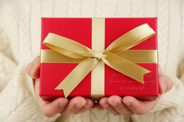 金色のリボンで結ばれた赤い箱のプレゼントの写真